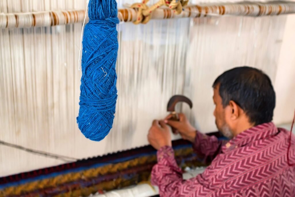 Back view man weaves carpet