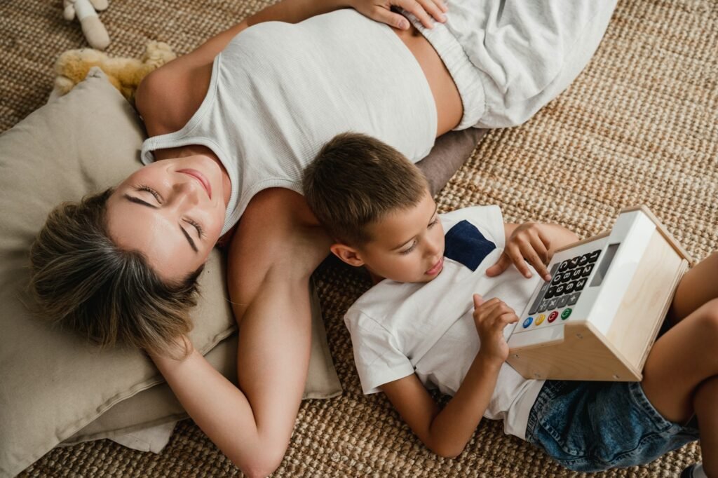 Relaxing mother and son using toy cash register and lying on a carpeted floor